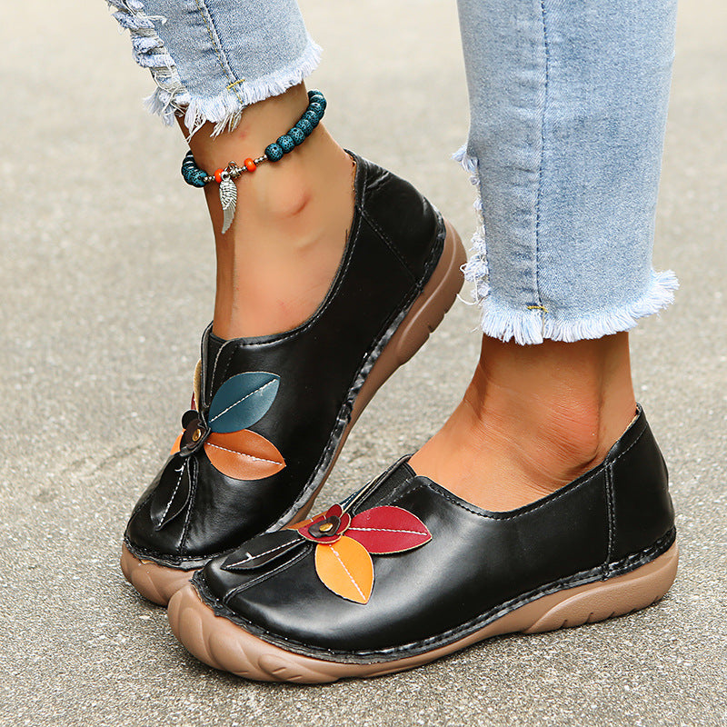 Black retro flower low-top loafers with orange blue floral pattern worn feet view