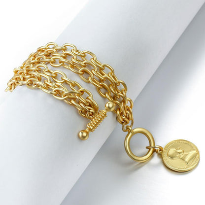 Close-up of gold alloy charm bracelet with coin detail"