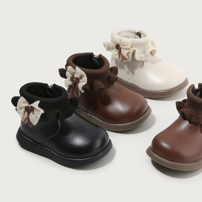 Baby boots with Fleece lining in black, brown, and white colors featuring decorative bows and rubber soles.